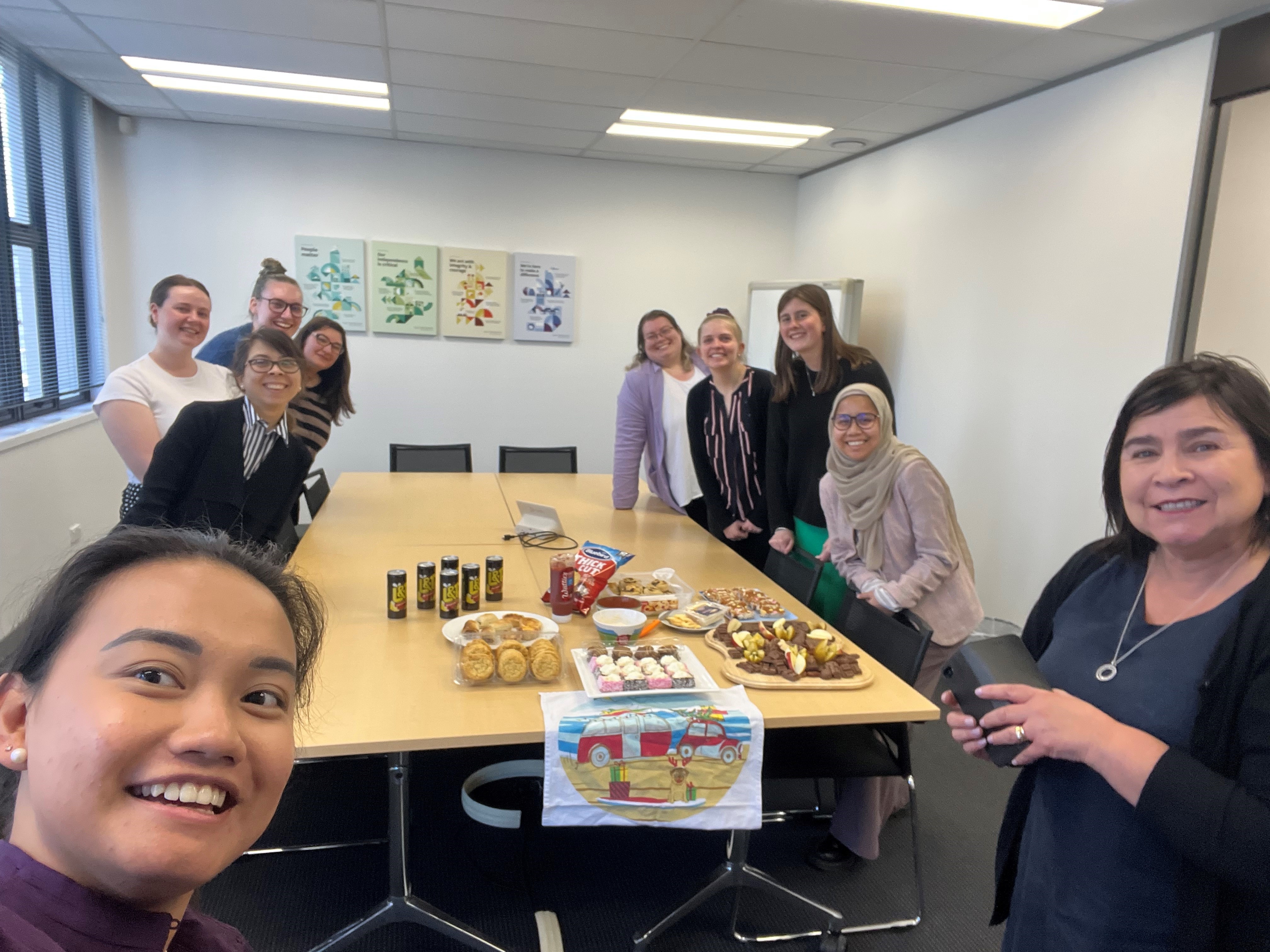 Image of a group of people around a table with morning tea items