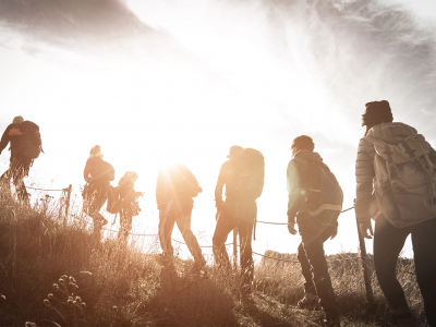 Group of people hiking up a hill, with a sunlit backdrop