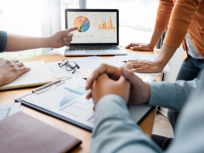 People meeting around a table, looking at graphs