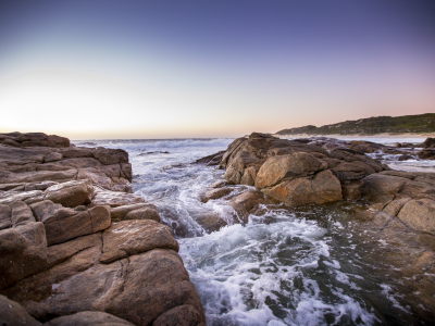 Waves streaming over rocks at sunset