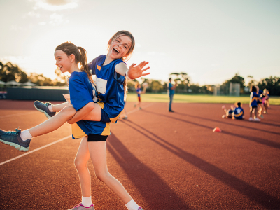 Image of two young girls on athletics track, having fun