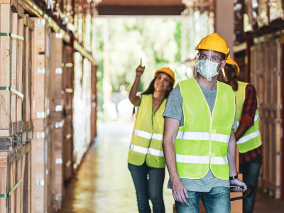 Image of three warehouse workers, wearing hardhats and masks