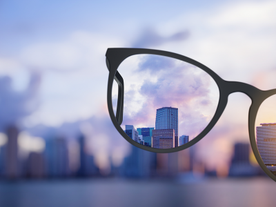 Image of glasses infront of a city skyline, blurry around the glasses