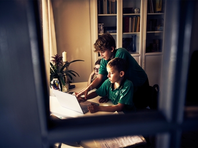 Three school children around a computer at home