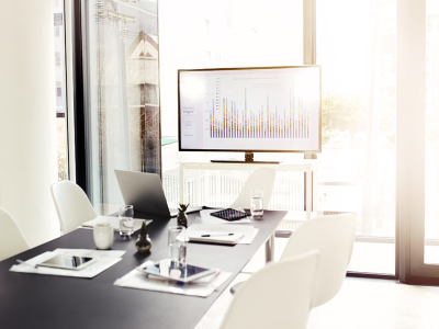 Image of a meeting table with a graph showing on a screen