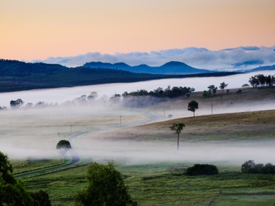 Image looking across a farm or rural landscape with fog rolling over hills