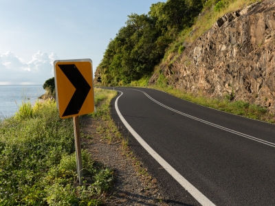 Image of a road sweeping right around a corner and a road sign