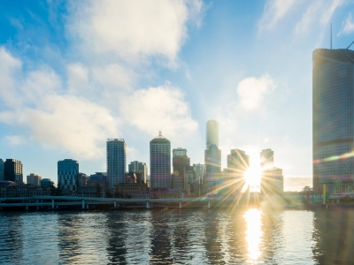 Blog thumbnail: View of Brisbane city over the river with sun peaking through buildings