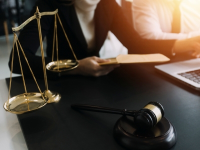Report thumbnail: 2 people at a desk in front of a computer, with justice scales and gavel on the desk 
