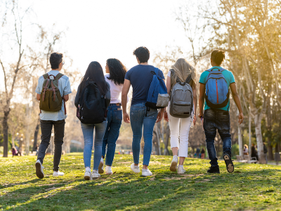 Image of 6 university-age students walking across a park or field