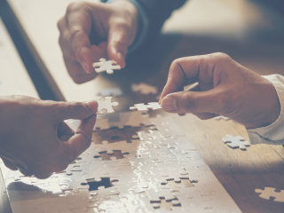 Image of three people holding puzzle pieces together