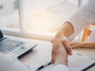 Image of two business people shaking hands over a contract