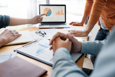 People meeting around a table, looking at graphs