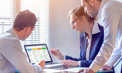 Three business people looking at a chart on a laptop