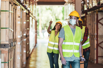 Image of three warehouse workers, wearing hardhats and masks