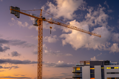 Image of a crane in front of part of an apartment building and sunset