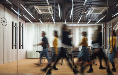 Image of an office with multiple blurred people walking past