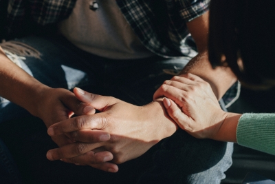 Report image: Person showing support by placing hand on the arm of another person with hands together