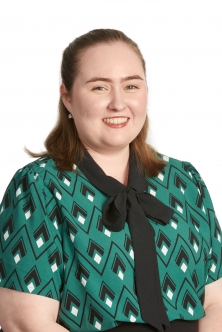 Woman in patterned business shirt, smiling. 